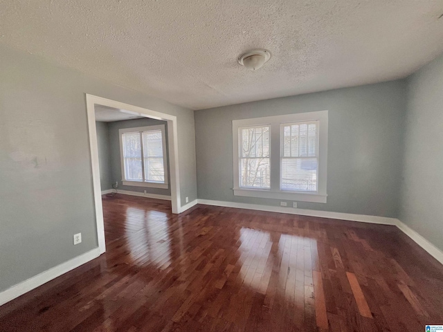 empty room with dark hardwood / wood-style floors and a textured ceiling