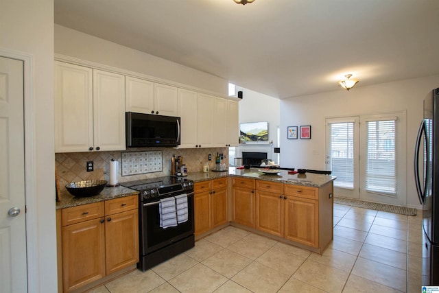 kitchen featuring electric range oven, black fridge, kitchen peninsula, and stone counters