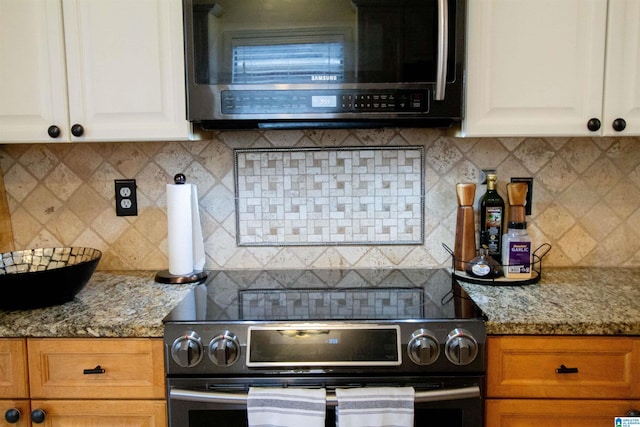 kitchen with stainless steel appliances, tasteful backsplash, white cabinets, and light stone counters