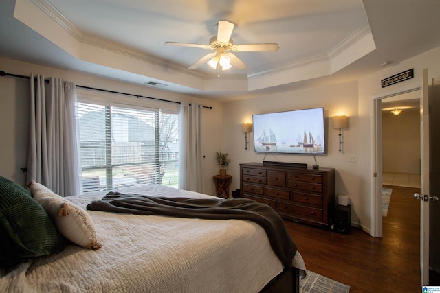 bedroom with dark wood-type flooring, ceiling fan, a tray ceiling, and crown molding