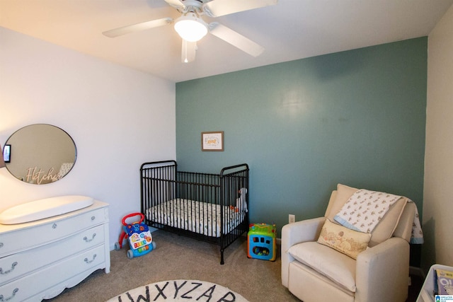 bedroom with light carpet, a nursery area, and ceiling fan