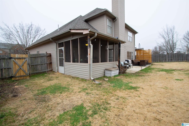 back of property with a patio area, a sunroom, and a lawn