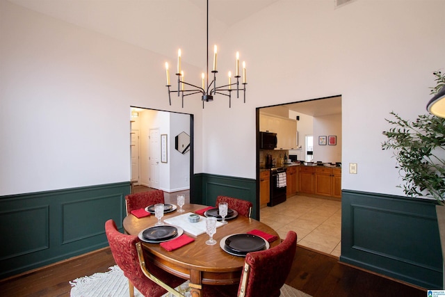 dining area with high vaulted ceiling and light hardwood / wood-style floors