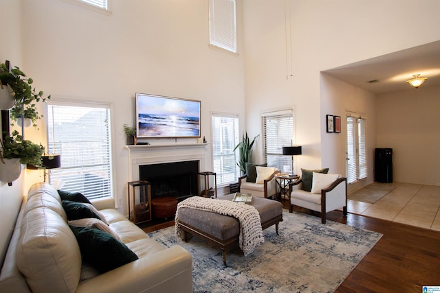 living room with a healthy amount of sunlight, dark wood-type flooring, and a towering ceiling