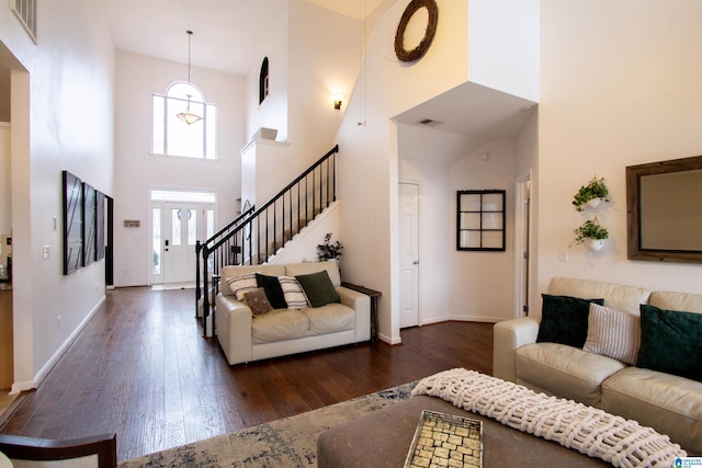 living room with a towering ceiling and dark hardwood / wood-style floors