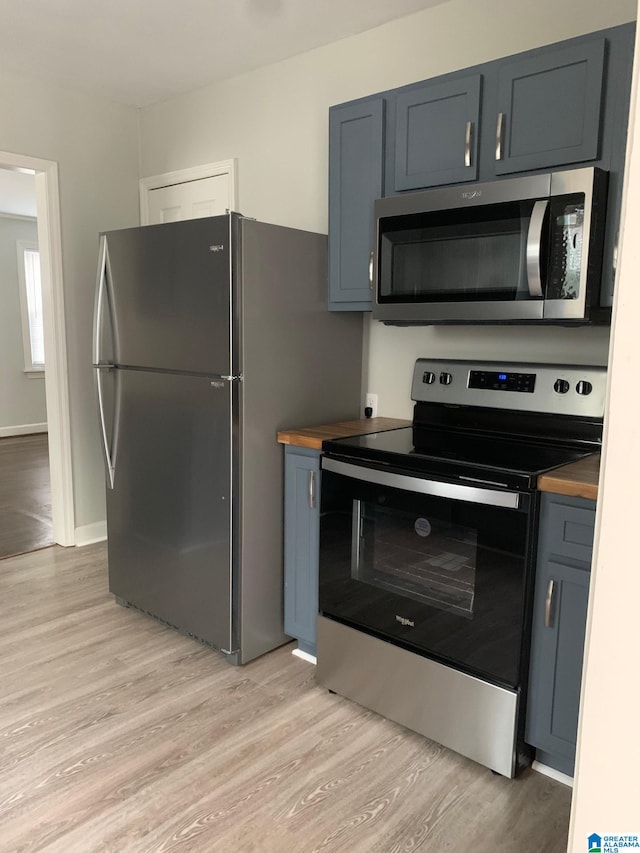 kitchen featuring appliances with stainless steel finishes, wooden counters, and light hardwood / wood-style flooring