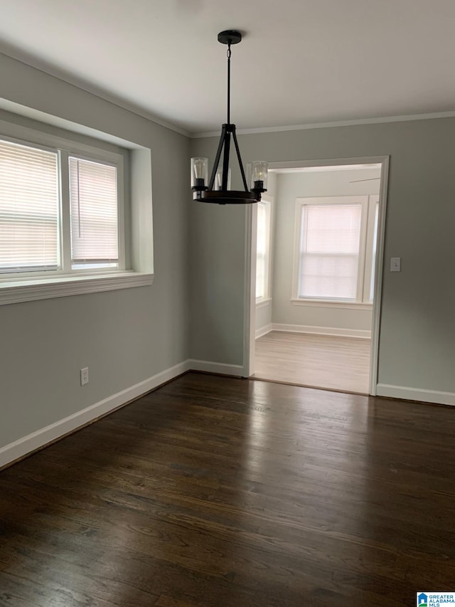 unfurnished dining area with ornamental molding, dark wood-type flooring, and an inviting chandelier