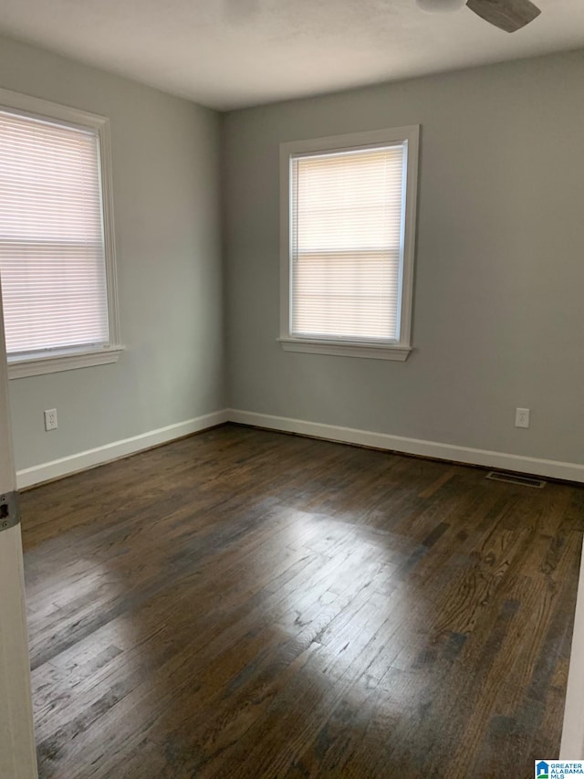 empty room featuring dark hardwood / wood-style flooring, a wealth of natural light, and ceiling fan