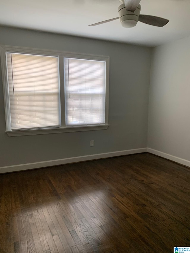 unfurnished room featuring a healthy amount of sunlight, dark wood-type flooring, and ceiling fan