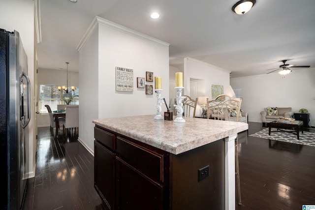 kitchen with pendant lighting, crown molding, stainless steel refrigerator, dark hardwood / wood-style floors, and a center island