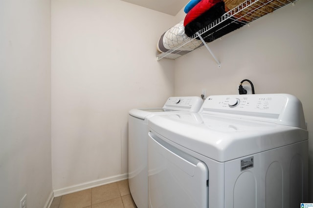 clothes washing area with light tile patterned floors and washer and clothes dryer