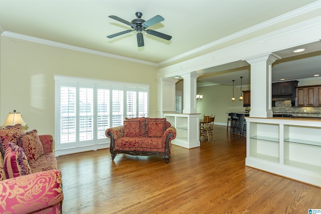 sitting room featuring ornamental molding, decorative columns, and wood-type flooring