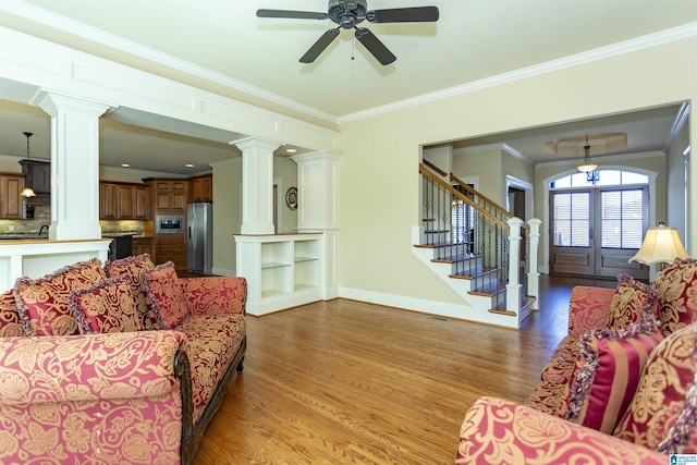 living room featuring light hardwood / wood-style flooring, french doors, ceiling fan, crown molding, and decorative columns