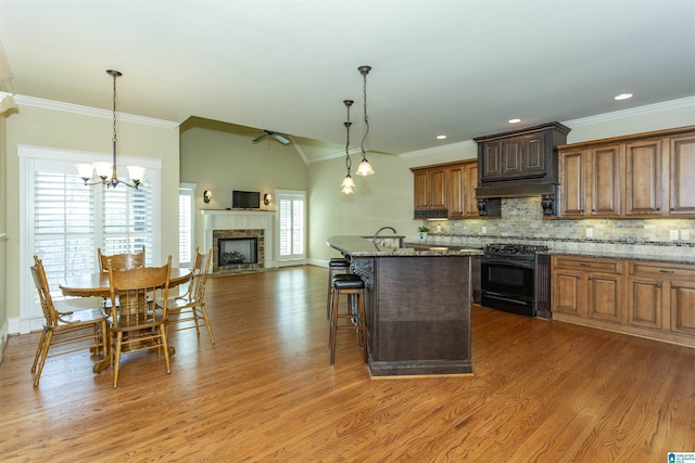 kitchen featuring decorative light fixtures, black range oven, a breakfast bar, and stone countertops