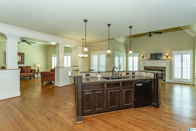 kitchen with a center island with sink, sink, decorative columns, black dishwasher, and dark brown cabinetry