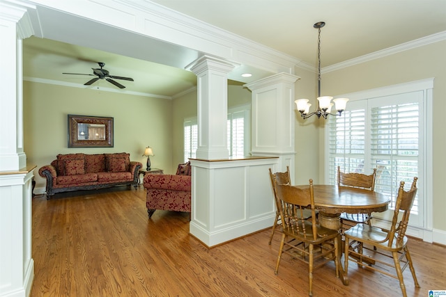 dining space featuring light hardwood / wood-style flooring, crown molding, and decorative columns