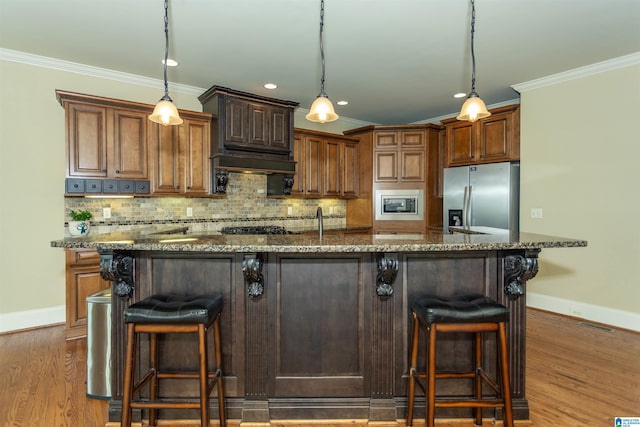 kitchen with a kitchen breakfast bar, stainless steel appliances, pendant lighting, and dark stone counters