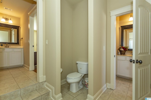 bathroom with toilet, vanity, and tile patterned flooring