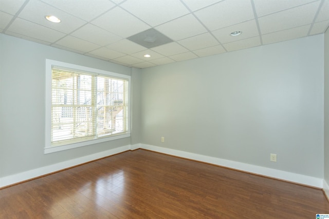 spare room featuring hardwood / wood-style flooring and a drop ceiling