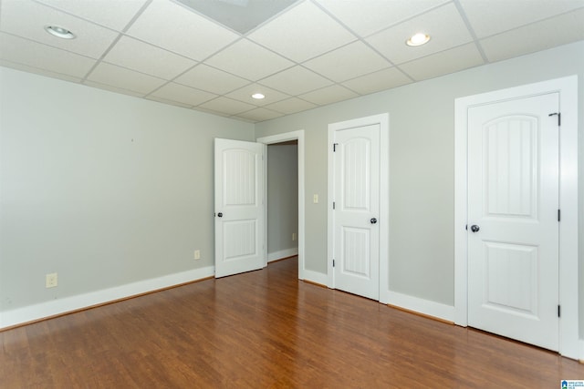 unfurnished room with dark wood-type flooring and a drop ceiling