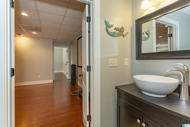 bathroom with a drop ceiling, vanity, and wood-type flooring