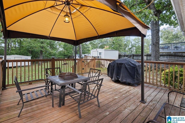 wooden deck with a gazebo, grilling area, and a storage unit