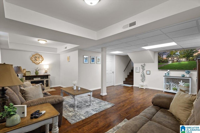 living room with dark hardwood / wood-style floors and a drop ceiling