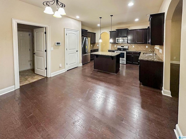 kitchen with pendant lighting, appliances with stainless steel finishes, a center island, and sink