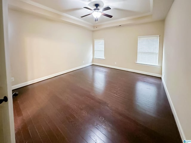 unfurnished room featuring dark wood-type flooring, ceiling fan, a tray ceiling, and crown molding