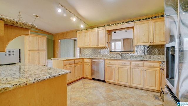 kitchen featuring tasteful backsplash, vaulted ceiling, light brown cabinets, stainless steel appliances, and light stone countertops