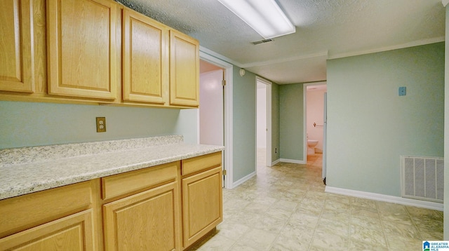 kitchen with light brown cabinetry and a textured ceiling