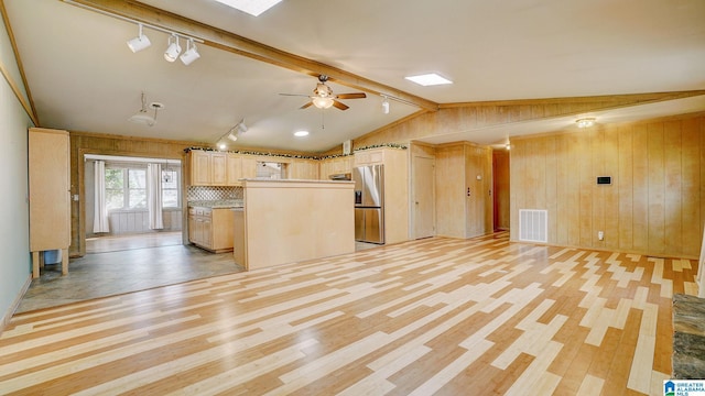 kitchen featuring lofted ceiling with beams, a center island, stainless steel fridge, and wooden walls