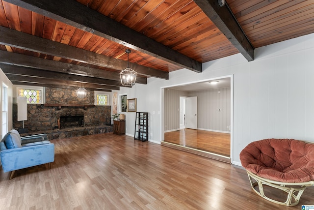 living room with wood ceiling, a stone fireplace, hardwood / wood-style floors, and beam ceiling