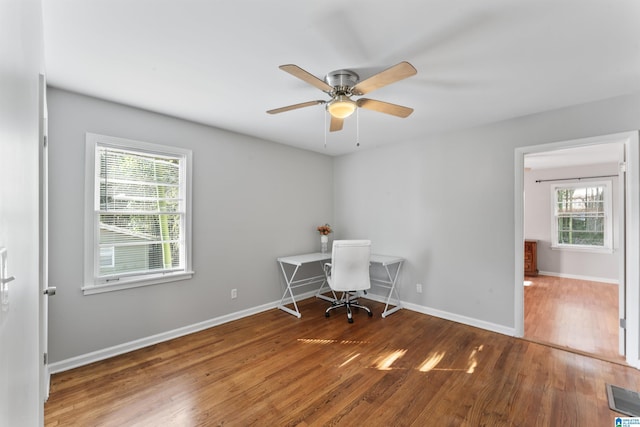 unfurnished office featuring dark wood-type flooring, ceiling fan, and plenty of natural light