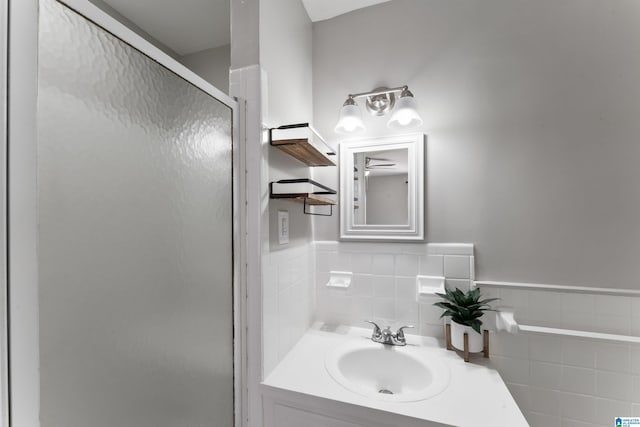 bathroom featuring vanity, a shower with shower door, and tile walls