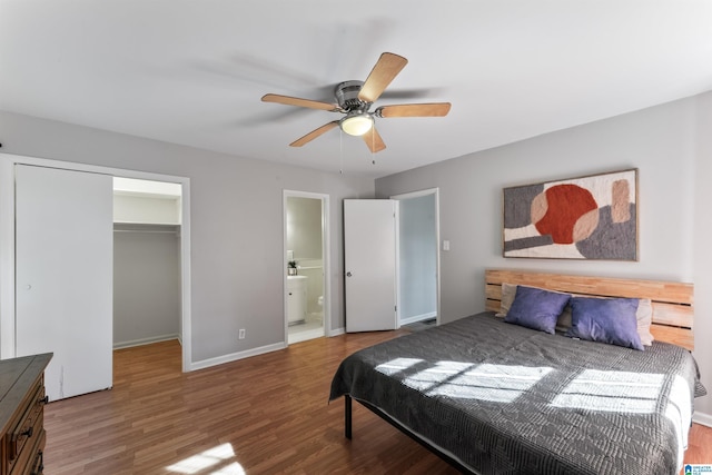 bedroom with ensuite bath, a spacious closet, a closet, hardwood / wood-style flooring, and ceiling fan