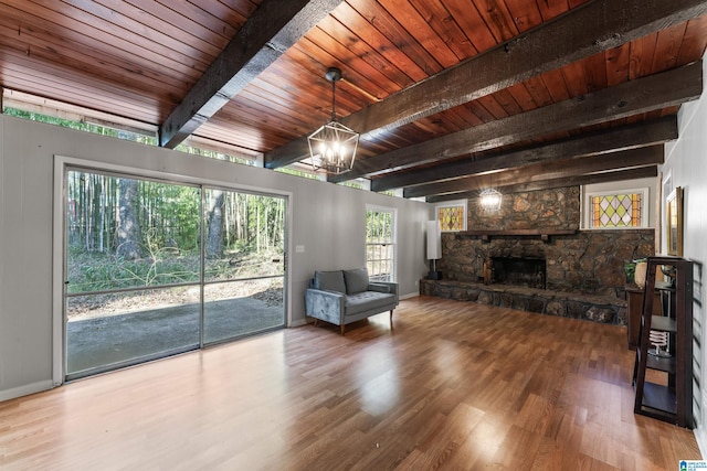 unfurnished living room featuring hardwood / wood-style floors, a fireplace, beamed ceiling, wooden ceiling, and an inviting chandelier