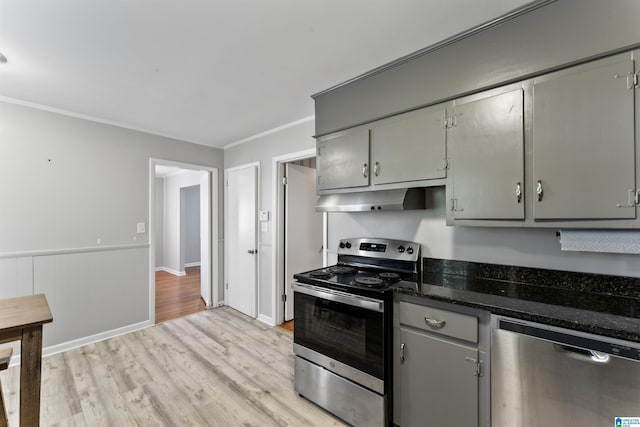 kitchen with gray cabinetry, dark stone counters, light wood-type flooring, ornamental molding, and stainless steel appliances