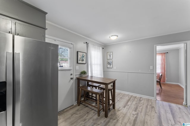 dining room with ornamental molding and light wood-type flooring