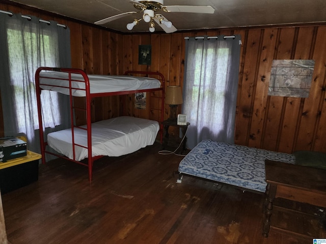 bedroom with hardwood / wood-style flooring, wooden walls, and multiple windows