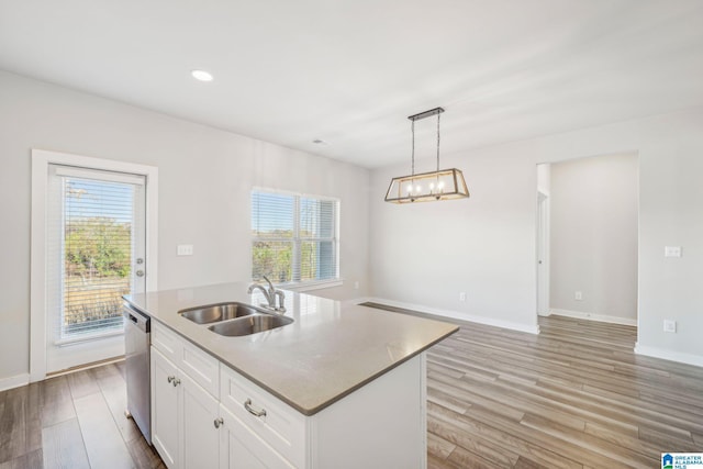 kitchen featuring sink, dishwasher, white cabinetry, hanging light fixtures, and an island with sink