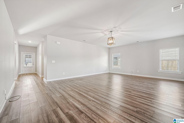 empty room featuring a chandelier and light wood-type flooring