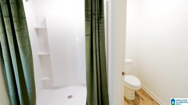 bathroom with a shower with curtain, wood-type flooring, and toilet