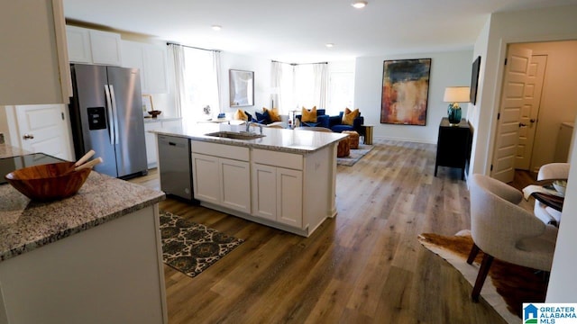 kitchen with white cabinetry, sink, a center island, stainless steel appliances, and light stone countertops