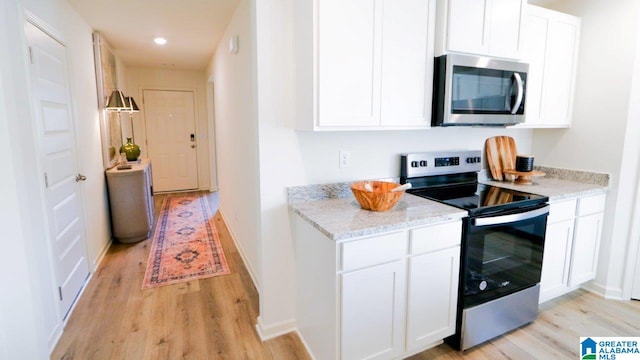 kitchen with white cabinetry, light stone counters, light hardwood / wood-style flooring, and stainless steel appliances