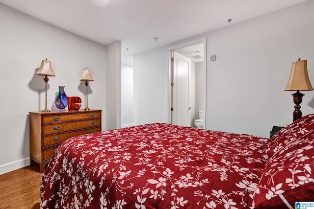 bedroom featuring ensuite bath and wood-type flooring