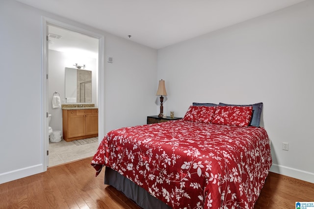 bedroom with connected bathroom and hardwood / wood-style flooring