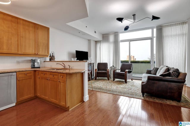 kitchen with sink, light wood-type flooring, stainless steel dishwasher, kitchen peninsula, and expansive windows