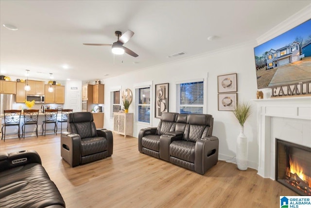 living room with crown molding, ceiling fan, and light hardwood / wood-style flooring