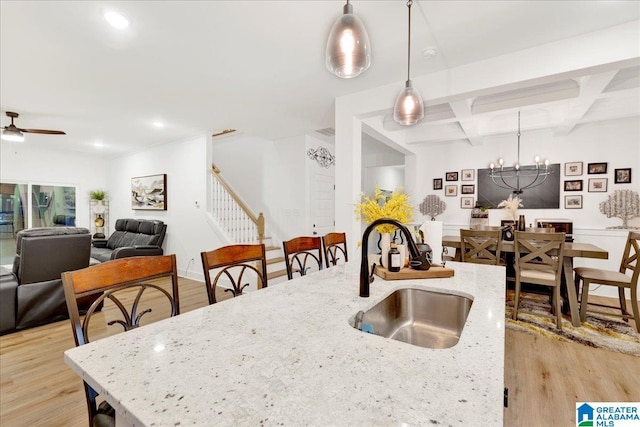 kitchen featuring coffered ceiling, sink, beamed ceiling, light hardwood / wood-style flooring, and pendant lighting